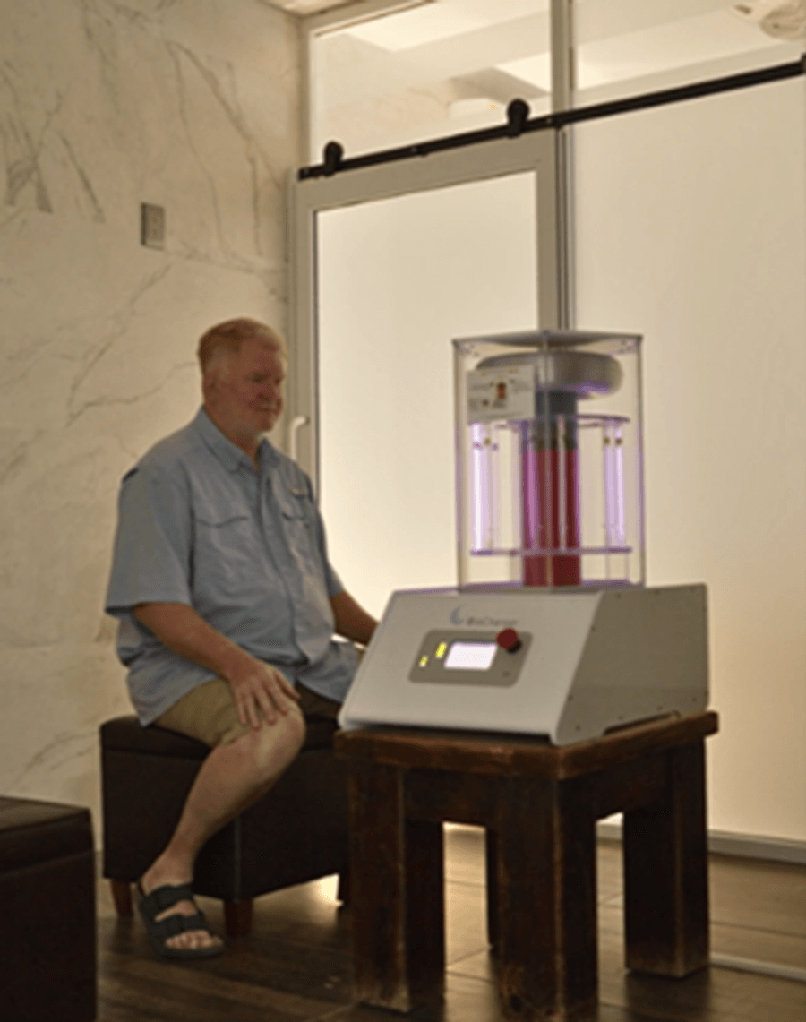 Patient seated next to a BioCharger device during a session