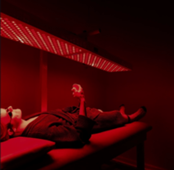 Person relaxing under a full-body red light therapy panel